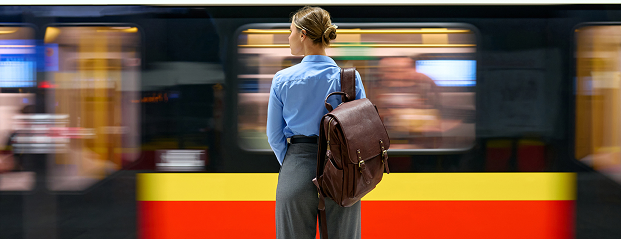 Image of subway train zooming past female who is waiting for her train